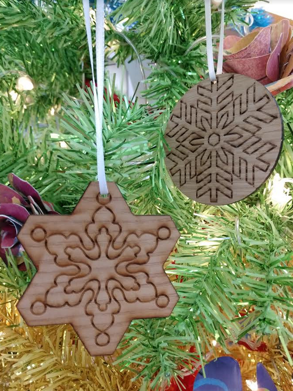 A picture of two laser-engraved wooden snowflake ornaments
