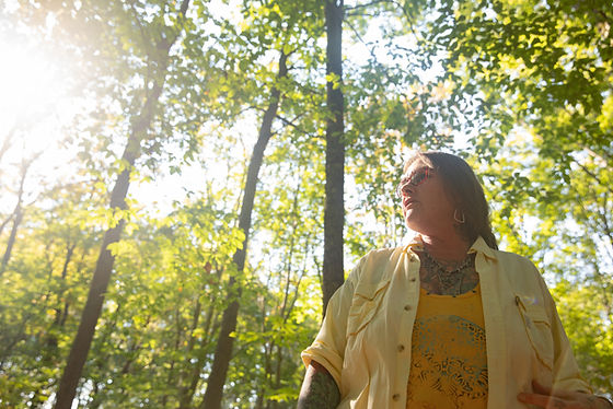 Photo of presenter Gina Kruzel standing in the woods. Photo credit Nate Swanson.