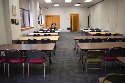 Large meeting room in the Nelsonville Public Library, including a set up of several tables with chairs.
