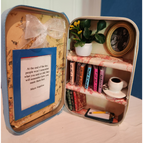 An open altoid tin with built on bookshelves, 1:12 scale books, and pottery