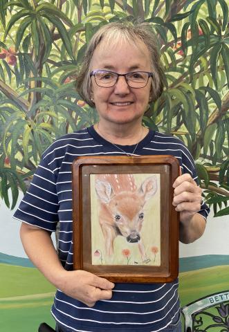 Human Standing in Front of Mural Holding Drawing of Fawn