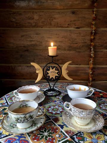 A lit candle behind filled tea cups