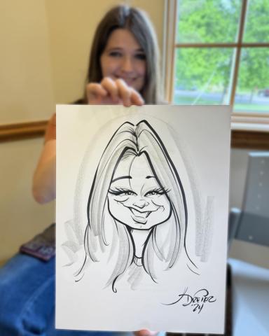 Coolville librarian Deidra shows off a caricature portrait of her drawn by Kurt Dreier