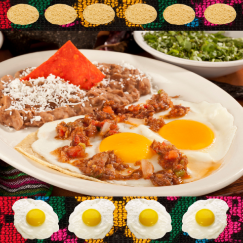 A plate of huevos rancheros with a side of refried beans and cheese. In the background is a bowl of green garnishes, colorful textiles, eggs, and tortillas.