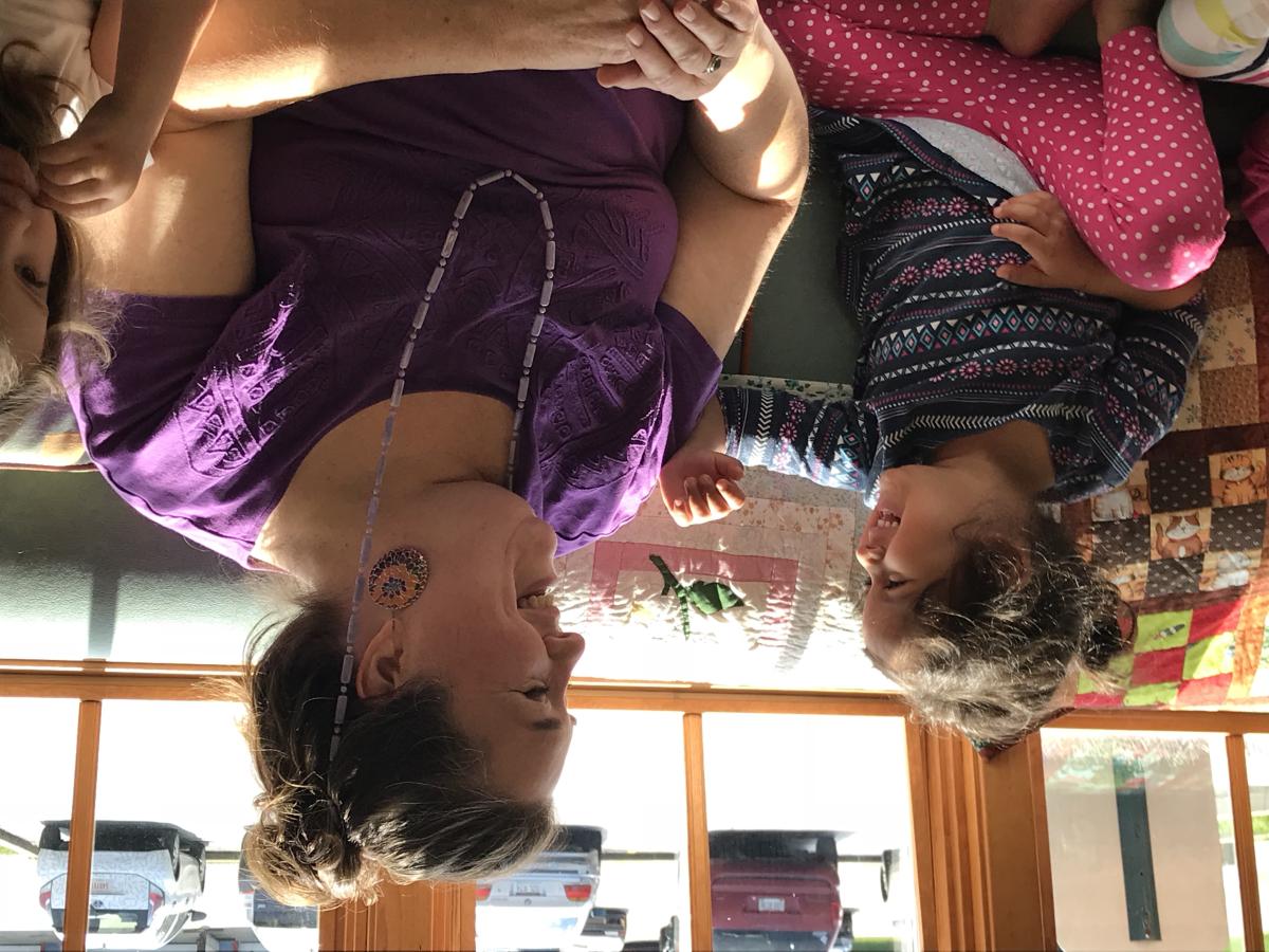 Woman and child smiling at each other while sitting on couch.