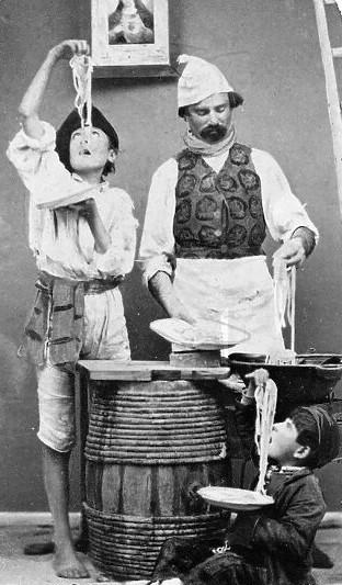 A black and white photo from Naples in 1869 shows a man and two kids eating spaghetti.