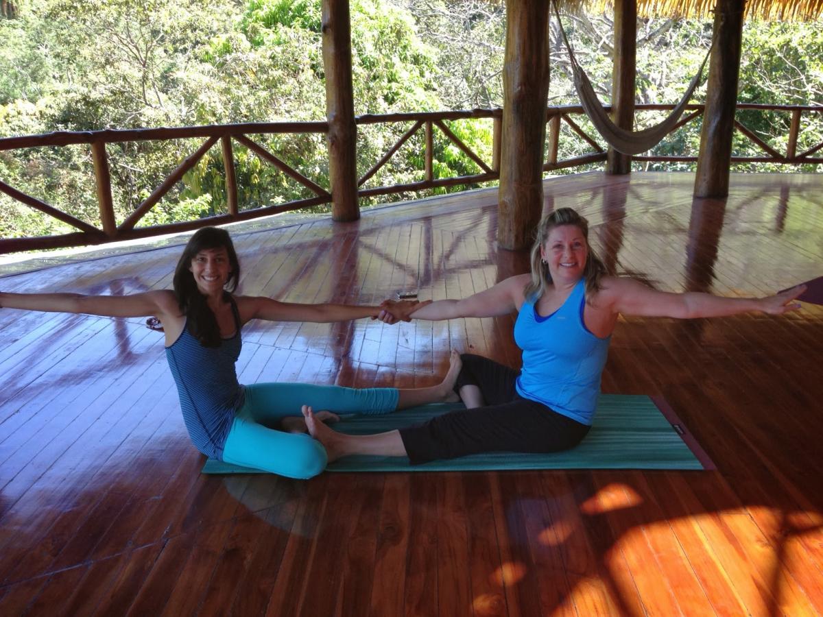 Two women assisting each other with yoga poses