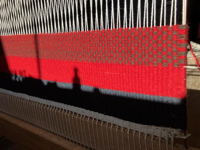 A close up of a red wool weaving by the presenter