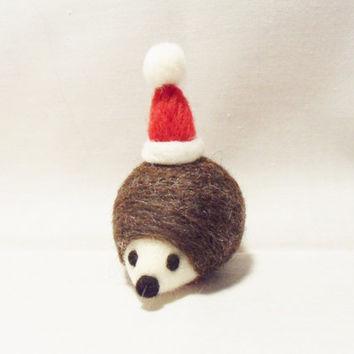 A photo of a felted hedgehog with a santa hat